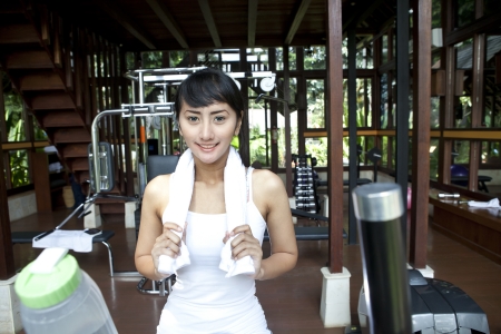 Healthy Asian woman smiling with towel in home gymの写真素材