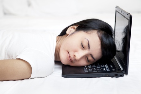 Young woman sleeping with laptop computer on the bedの写真素材