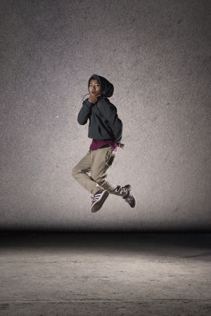 Cool looking dancer jumping on grey grunge wall backgroundの写真素材
