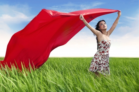 Woman holding red scarf with opened arms expressing freedom outdoorの写真素材