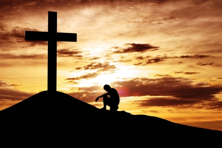 A man making a confession to the cross, shot under dawn skyの写真素材