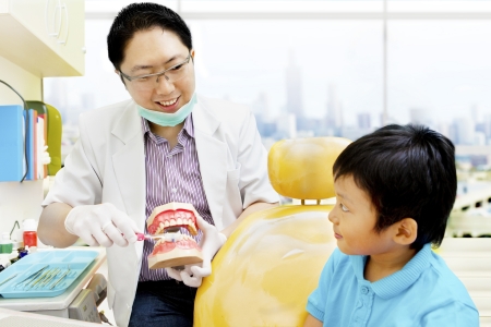 Asian destist showing a boy  how to brush his teeth properlyの写真素材