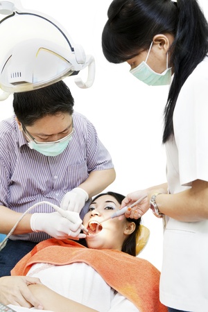 Asian dentist and his assistant carrying out a thorough oral cavity examinationの写真素材