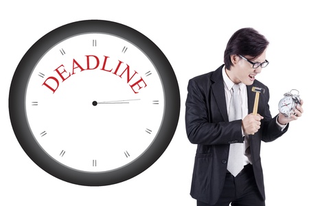 Angry asian businessman using hammer to hit alarm clock. isolated on white backgroundの写真素材