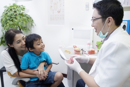 Portrait of male dentist show a sample of braces to his patient at officeの写真素材