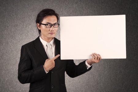 Young businessman pointing at an empty copy space. shot in studioの写真素材