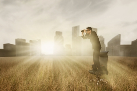 Business man with binoculars looking to the future outdoorの写真素材