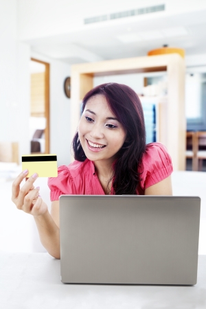 Satisfied woman shopping online with laptop and a credit card at home の写真素材