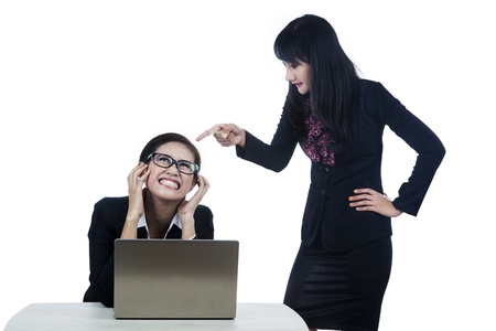Businesswoman yelling at her subordinate while working with her laptopの写真素材