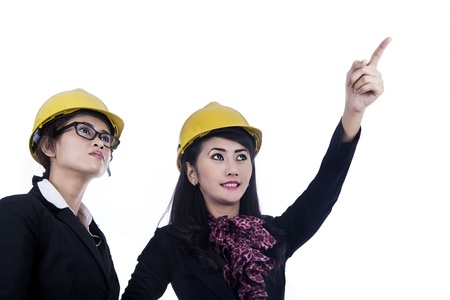 Two female architects wearing yellow helmet isolated in whiteの写真素材