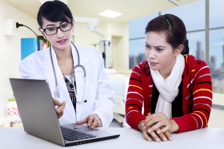 Female doctor is explaining her diagnosa to her patient via laptopの写真素材