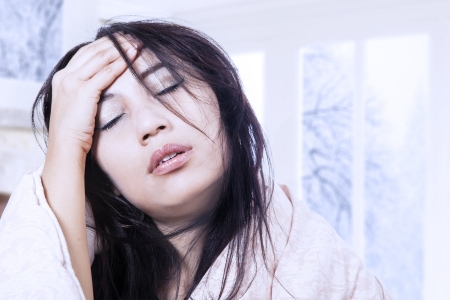Asian woman is having a headache with fever at home Asian woman is having a headache with fever at home