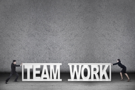 Concept of a teamwork in business showing by two people pushing teamwork textの写真素材