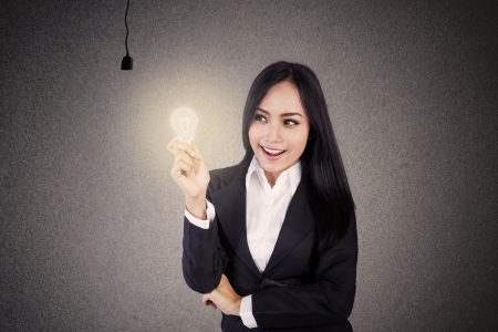 Businesswoman smiling because she got one lit light bulbの写真素材