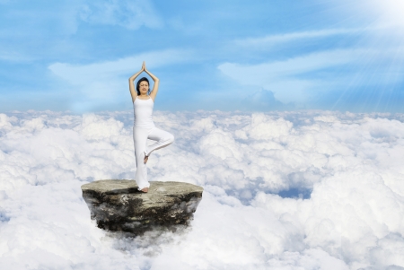 Beautiful standing yoga position by Asian woman above cloudsの写真素材