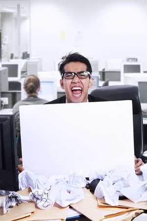 Businessman is screaming showing blank white paper at officeの写真素材