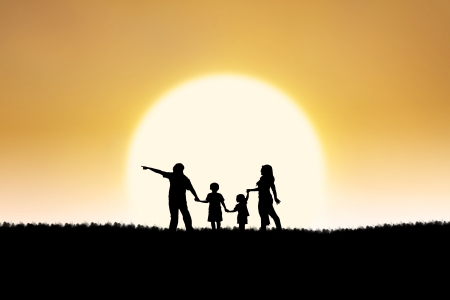 Silhouette of family walking on the field under the sunsetの写真素材