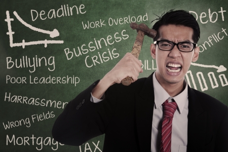 Frustrated businessman hitting his head with hammerの写真素材