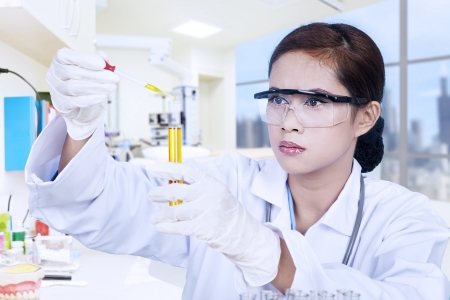 Young female scientist holding yellow liquid in a flaskの写真素材