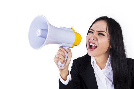 Business woman with megaphone yelling and screaming isolated on white backgroundの写真素材