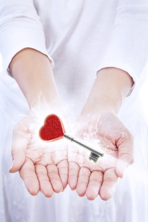 A woman presented a love key with red heart shape on isolated white backgroundの写真素材