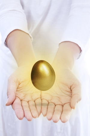 A girl is giving a shiny golden egg isolated on whiteの写真素材