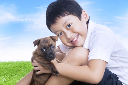 Happy boy and puppy outdoors under blue skyの写真素材