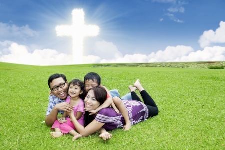 Happy Asian family is laying on the grass by the Crossの写真素材