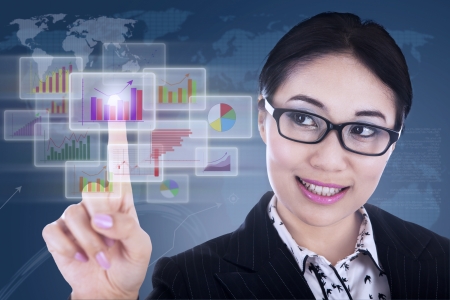 Businesswoman is clicking on futuristic touchscreen with diagramsの写真素材