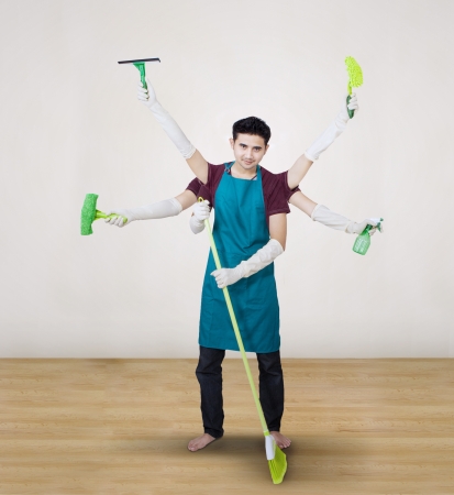 Young cleaner man with multi hands at homeの写真素材