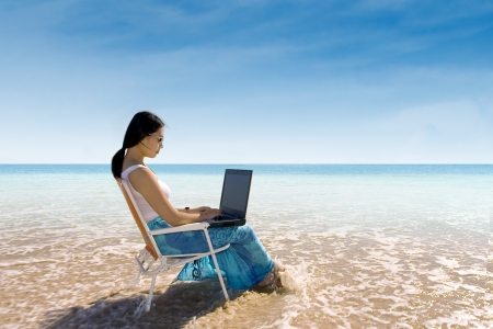 Attractive woman working with laptop on the beachの写真素材