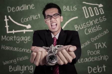 Angry businessman with hands chained at classroomの写真素材
