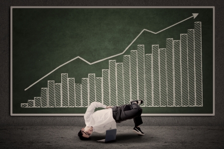 Businessman dancing in front of profit bar chart at classroomの写真素材