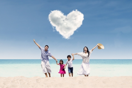 Happy Asian family run at beach under love cloudの写真素材
