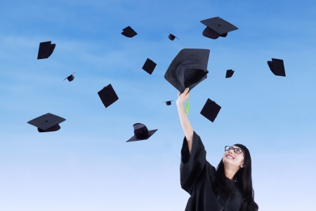 Asian graduate throw graduation cap under blue skyの写真素材