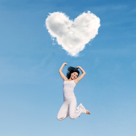 Asian woman jumping happily under heart cloudの写真素材