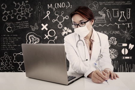 Female doctor with stethoscope and laptop writing on the paper to make a prescription. isolated on whiteの写真素材