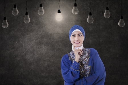 Asian female muslim is thinking under lightbulbs in classの写真素材