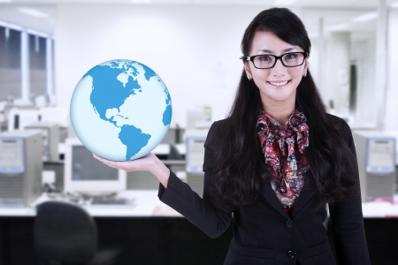 Businesswoman is holding blue world global at officeの写真素材
