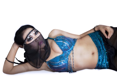 Attractive female belly dancer is lying on the ground - isolated on white