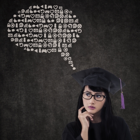 Thoughtful female graduate with abstract cloud in classの写真素材