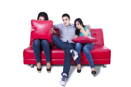 Friends - a man an two woman watching a scary movie in TV isolated on white backgroundの写真素材