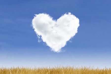 Blue sky and heart shaped cloud over yellow grassの写真素材