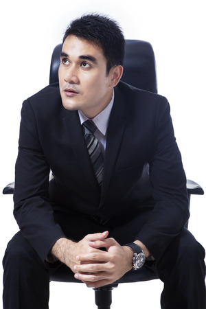 Asian businessman sitting on office chair looking at copyspaceの写真素材