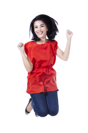 Excited young woman jumping in air isolated on white backgroundの写真素材