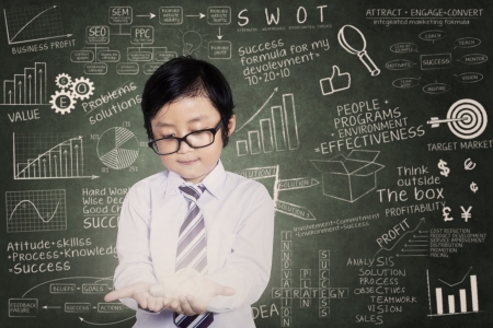 Asian boy holding a light bulb with chalkboard の写真素材