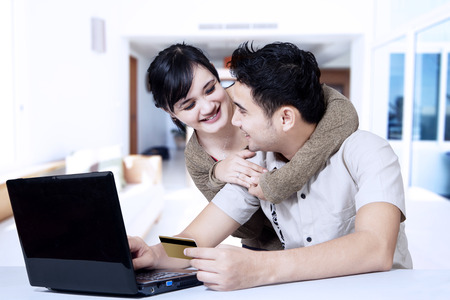 Portrait of happy asian couple online shopping at homeの写真素材