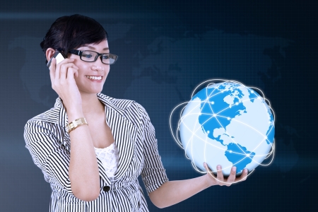 Portrait of young asian woman calling and holding globeの写真素材