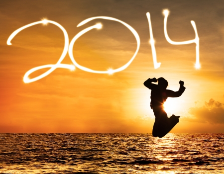 Silhouette of woman jumping and drawing 2014 at sunsetの写真素材