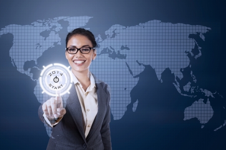 Young businesswoman touching futuristic touchscreen on blue world map backgroundの写真素材